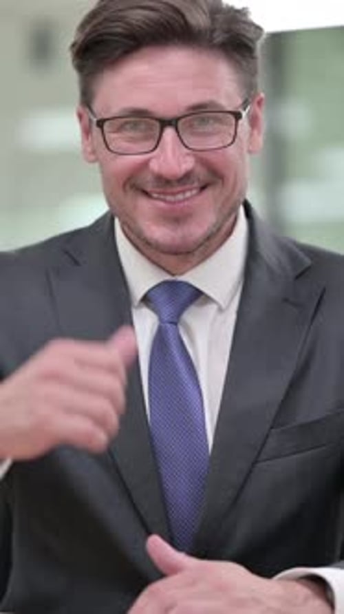 Cheerful Businessman Giving a Thumbs Up Indoors