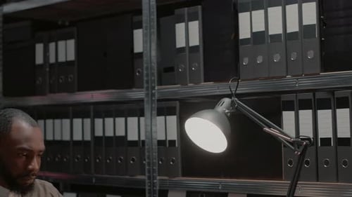 Man Reviews Files Under Desk Lamp