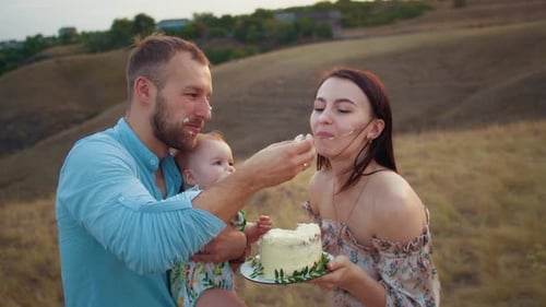 Happy Family with Baby Celebrate First Year Eat Cake in Field at Sunset Autumn and Lifestyle