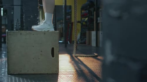 Legs of Unrecognisable Girl Doing Set of Box Jumps in Gym