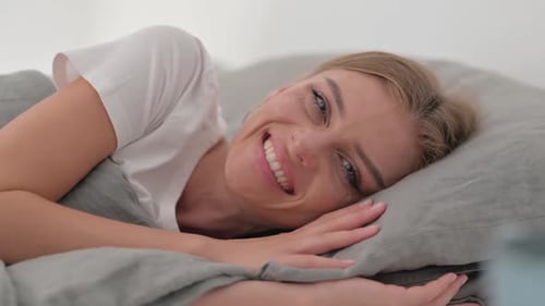 Close up of Smiling Young Woman Lying on Side in Bed