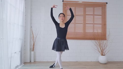 Graceful Young Woman Practicing Ballet Moves in Studio