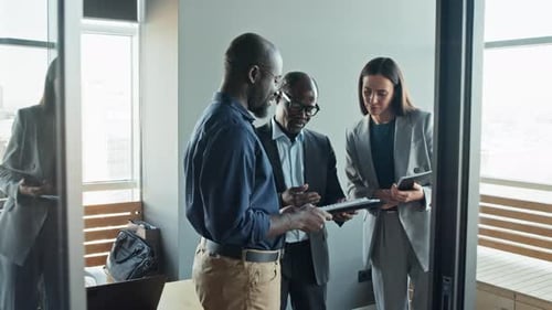 Business Team Standing In Office and Discussing Reports