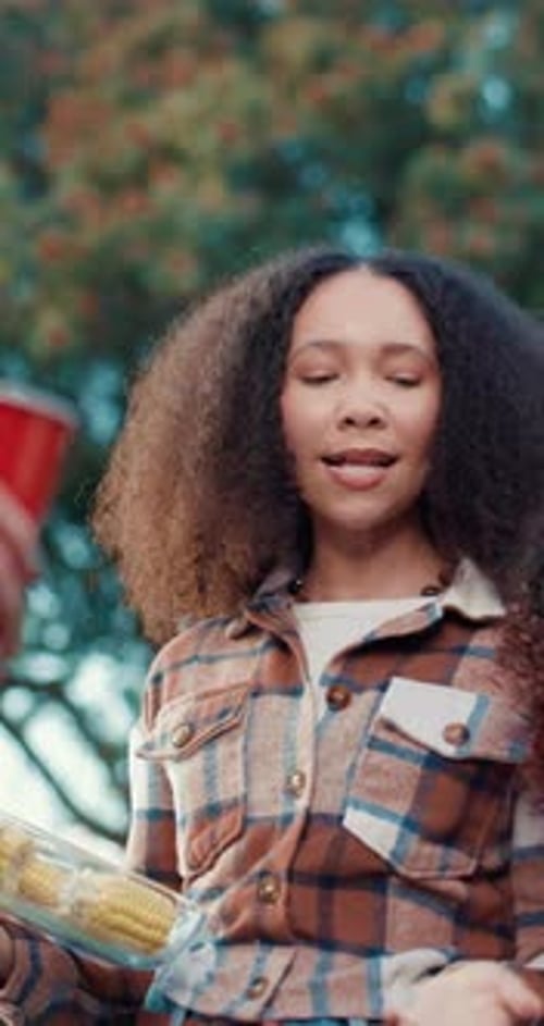 Smiling Woman Holding Corn on the Cob Outside