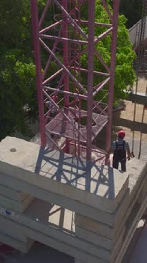 Vertical Video Aerial View Of Construction Workers Assembling A Tower Crane Piece By Piece On A Busy