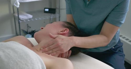 Woman receives neck massage from practitioner indoors