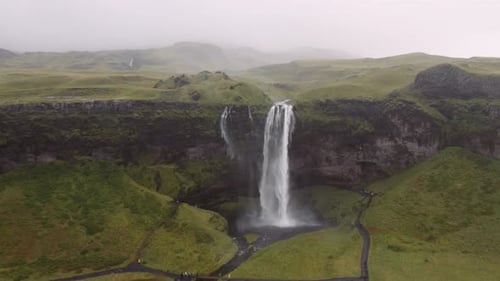 Icelandic Waterfall Cascades Through Green Landscape