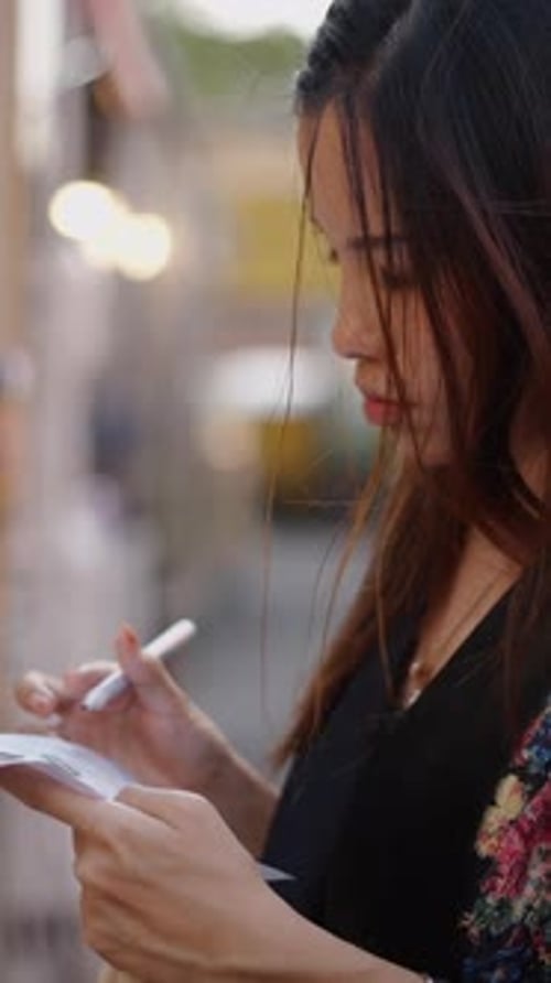 A Darkhaired Woman Writes Her Order on a Piece of Paper