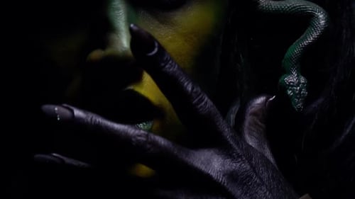 Medusa hiding her face behind her black hand, close up