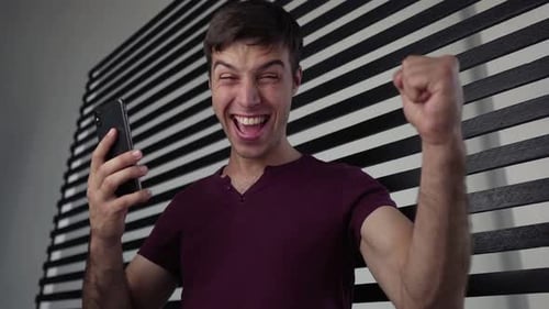 Man Celebrates Success While Using Mobile Phone