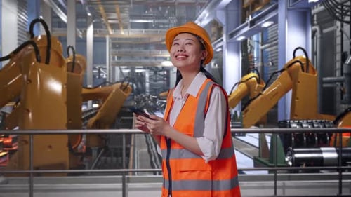 Side View Of Asian Female Engineer Using Smartphone With Robotic Arms