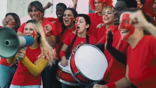 Multiracial football fans exulting while watching soccer game at stadium