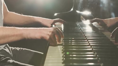 Hands Play Piano Keys in Dramatic Lighting