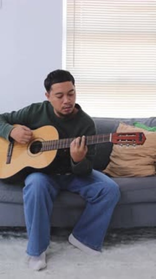 Young Adult Playing Acoustic Guitar Indoors