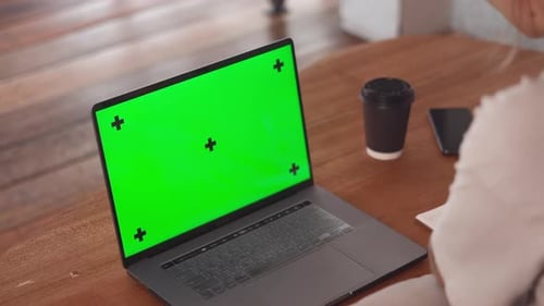 Green Screen laptop Girl watching video webinar online lesson and writing in notepad