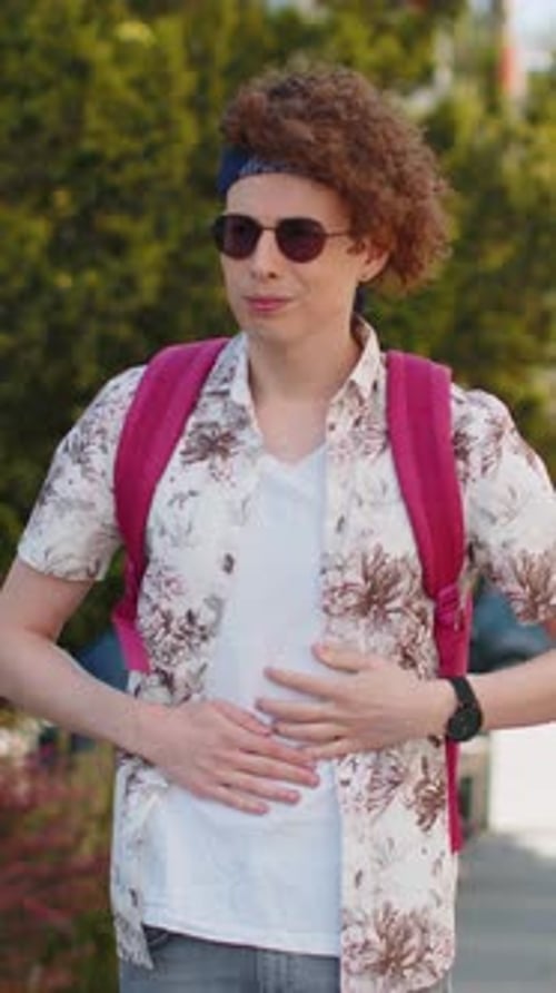 Man With Curly Hair Holds Stomach In Pain Outdoors