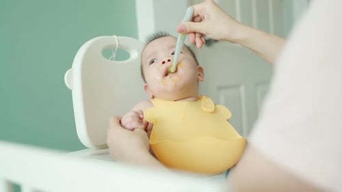 Cute Baby Having Food in Highchair Indoors