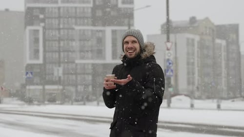 Smiling Man Enjoys Snowy Day with Coffee