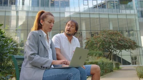 Two People Man and Woman Discussing Financial Market Data Using Laptop