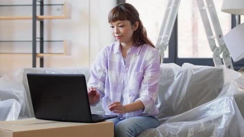 Moving, People And Real Estate Concept - Happy Smiling Asian Woman With Laptop Computer And Boxes...