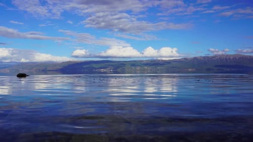 Lake panorama with clean calm water reflecting beautiful clouds on blue sky
