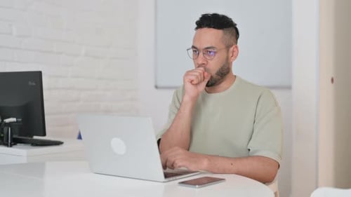 Man Working at Laptop Coughing Indoors