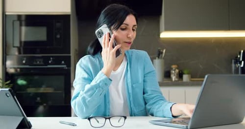 Woman Working from Home While Talking on Phone