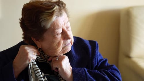 Senior Woman Buttons Jacket Indoors