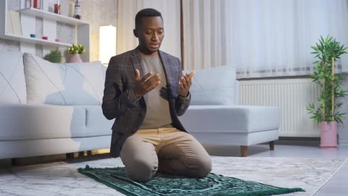 Young Man Kneeling and Praying in Living Room
