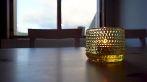 Golden candle holder on table with soft focus, warm indoor mood, dusk light from window