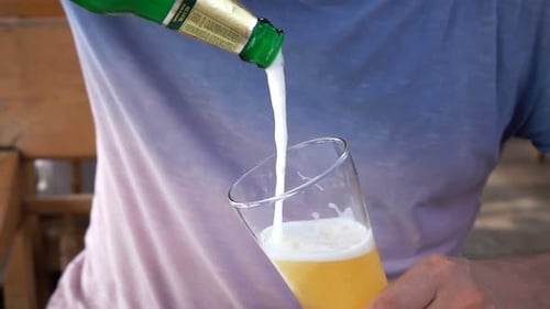 Man pouring golden beer into glass in cafe super slow motion