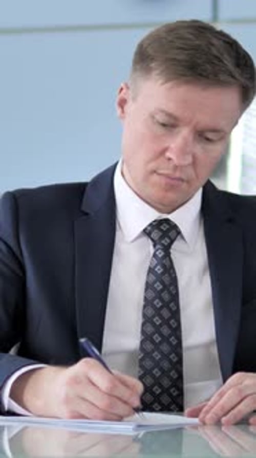 Professional Man Signing Legal Documents at Office Desk