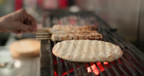 Closeup of a Man's Hand Flipping a Flatbread on the Grill