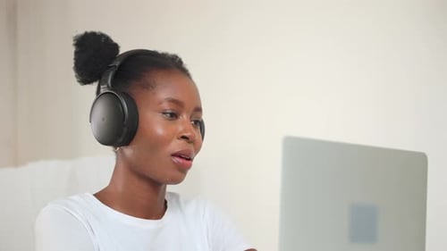 Young Adult with Headphones Looking at Laptop