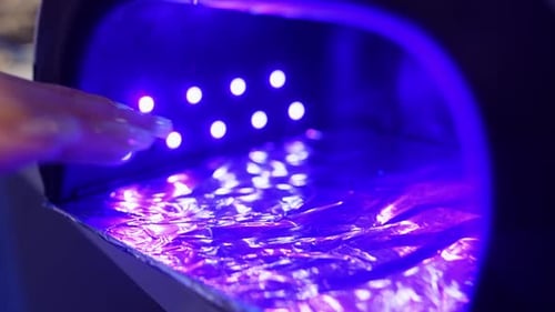 Woman Manicuring Nails in a Blue Light Box