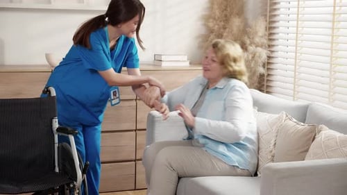 Nurse Helps Senior Woman into Wheelchair