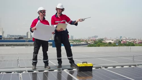 Two engineer checking solar energy system looking blueprint for planning installation solar panel.