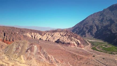 Aerial view drone flying over scenic rocky mountains landscape with a clear blue sky.