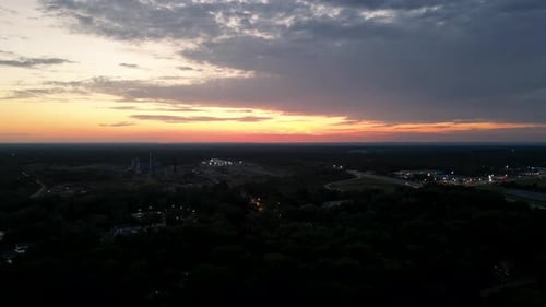 A captivating view of an industrial area at dusk, with a vibrant sunset lighting up the horizon. Per