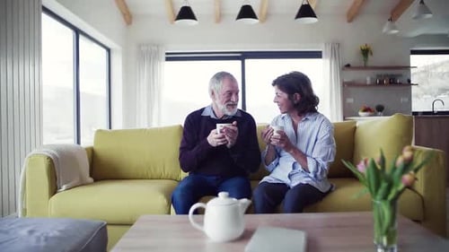 Senior Couple Relaxing on Sofa with Hot Drinks