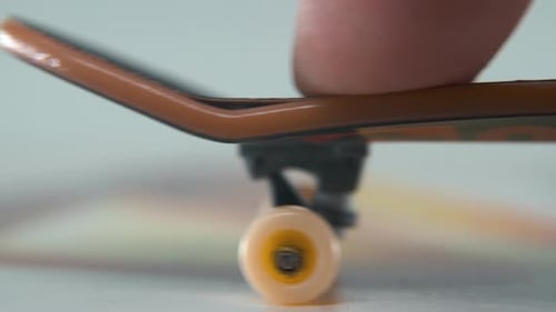 A hyper detailed shot of a mini skateboard, tiny white wheels, riding fingerboard from left to right