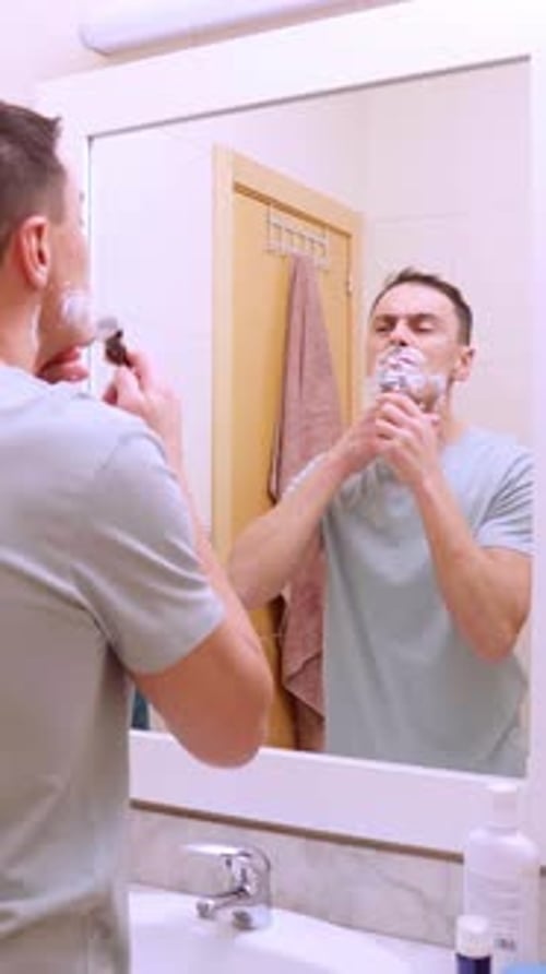 Homem raspando a barba no espelho do banheiro