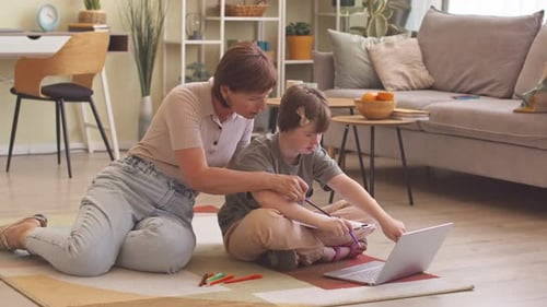 Woman Assists Girl with Drawing at Home