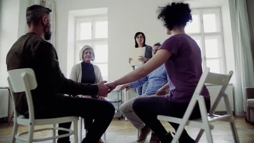 Men And Women Sitting In A Circle During Group Therapy, Supporting Each Other.