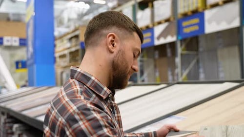 A Man Looks at Different Types and Colors of Floor Coloring in a Store