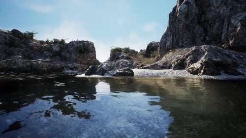 Tranquil Rocky Shoreline Reflecting Clear Blue Sky on a Peaceful Afternoon
