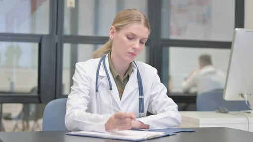Young Female Doctor Writing Medical Documents in Clinic