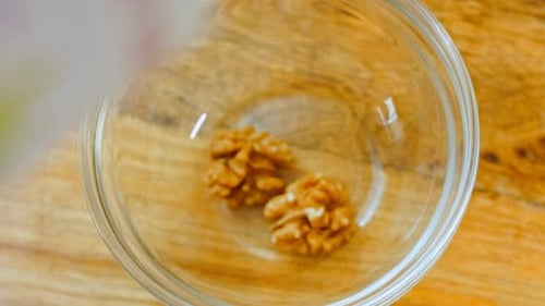 Walnuts Poured into Glass Bowl on Wooden Table