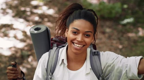 Young African American Woman Enjoying Hiking in Forest With Backpack and Mat