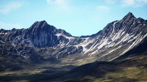 Hillside Overgrown with Dry Grass Against the Backdrop of Snowcapped Mountains